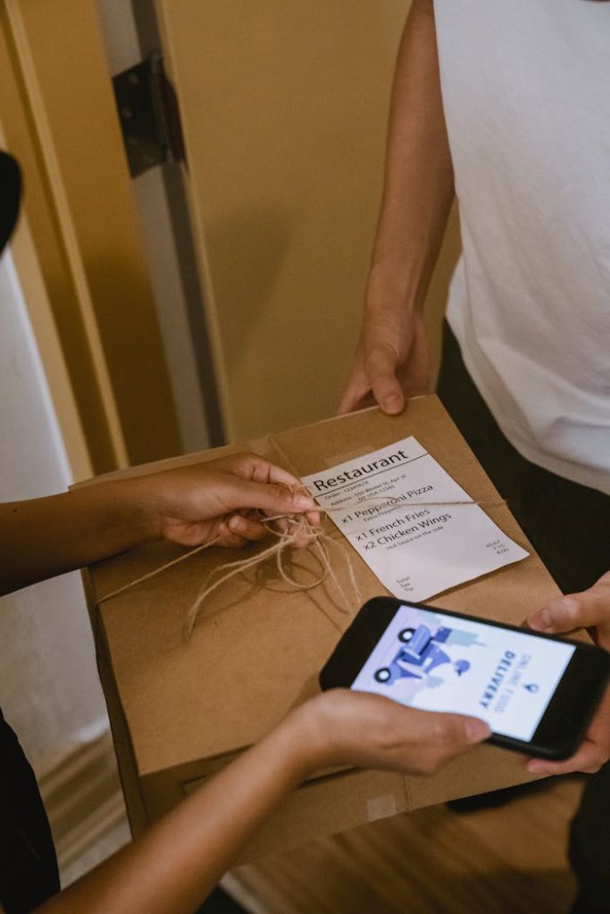 Close-up of food delivery interaction with smartphone and package indicating online order.